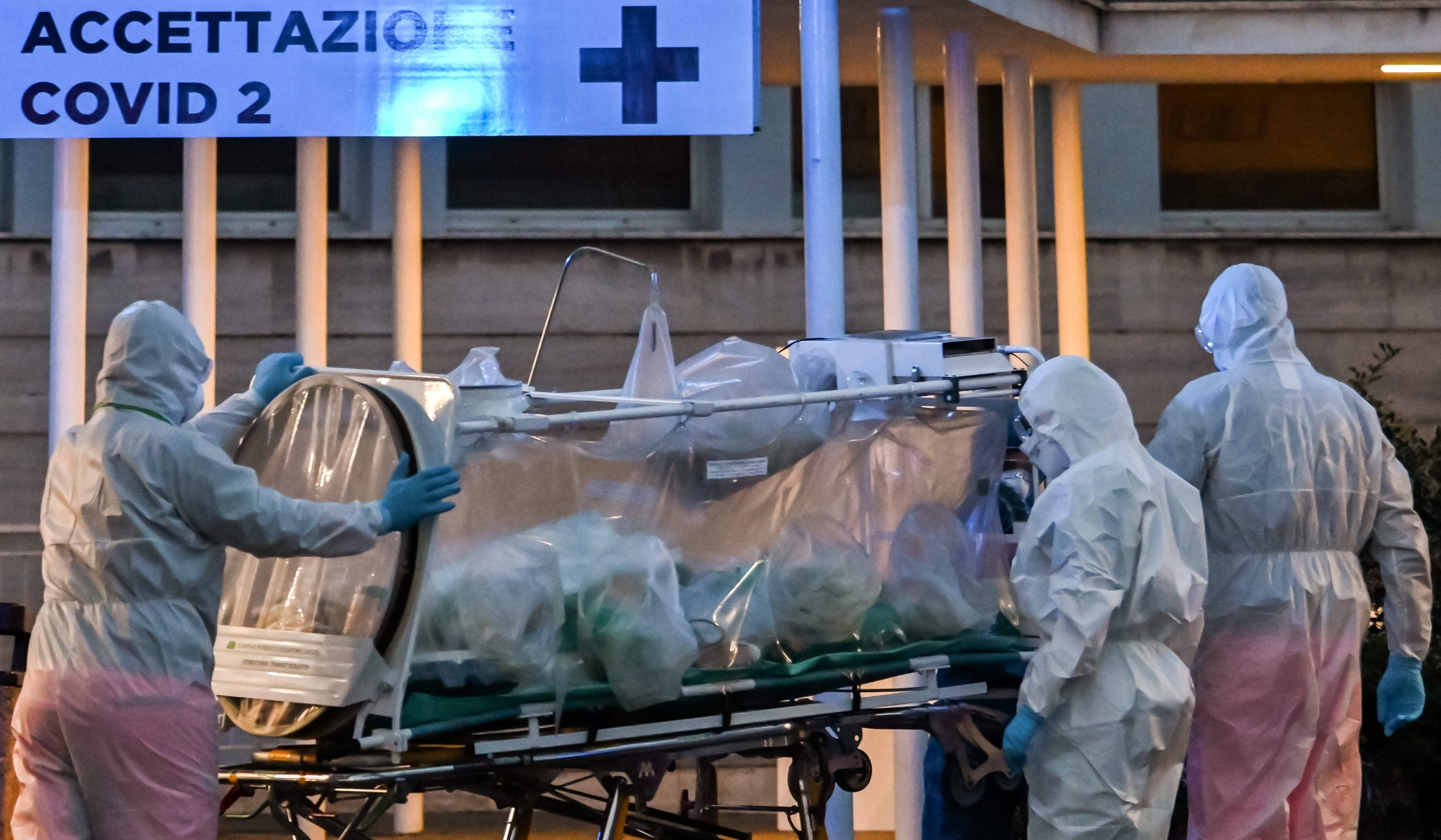 Médicos con trajes protectores para prevenir el coronavirus llevan a un paciente al hospital temporal Columbus Covid 2 en Italia. (AFP / ANDREAS SOLARO).